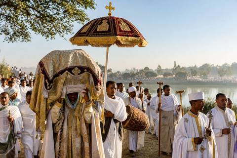 Timket procession with Ethiopian Orthodox clergy carrying a covered tabot beneath a ceremonial umbrella