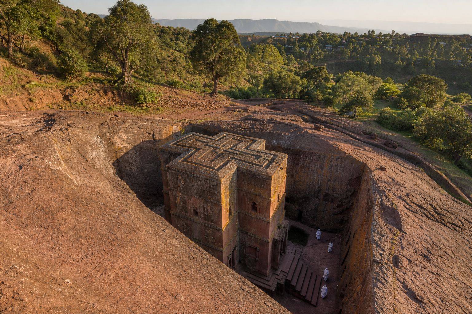 Biete Ghiorgis carved into red rock at Lalibela with pilgrims walking through the surrounding trenches
